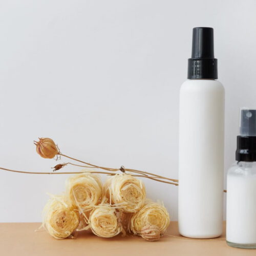White spray bottle beside dried flowers